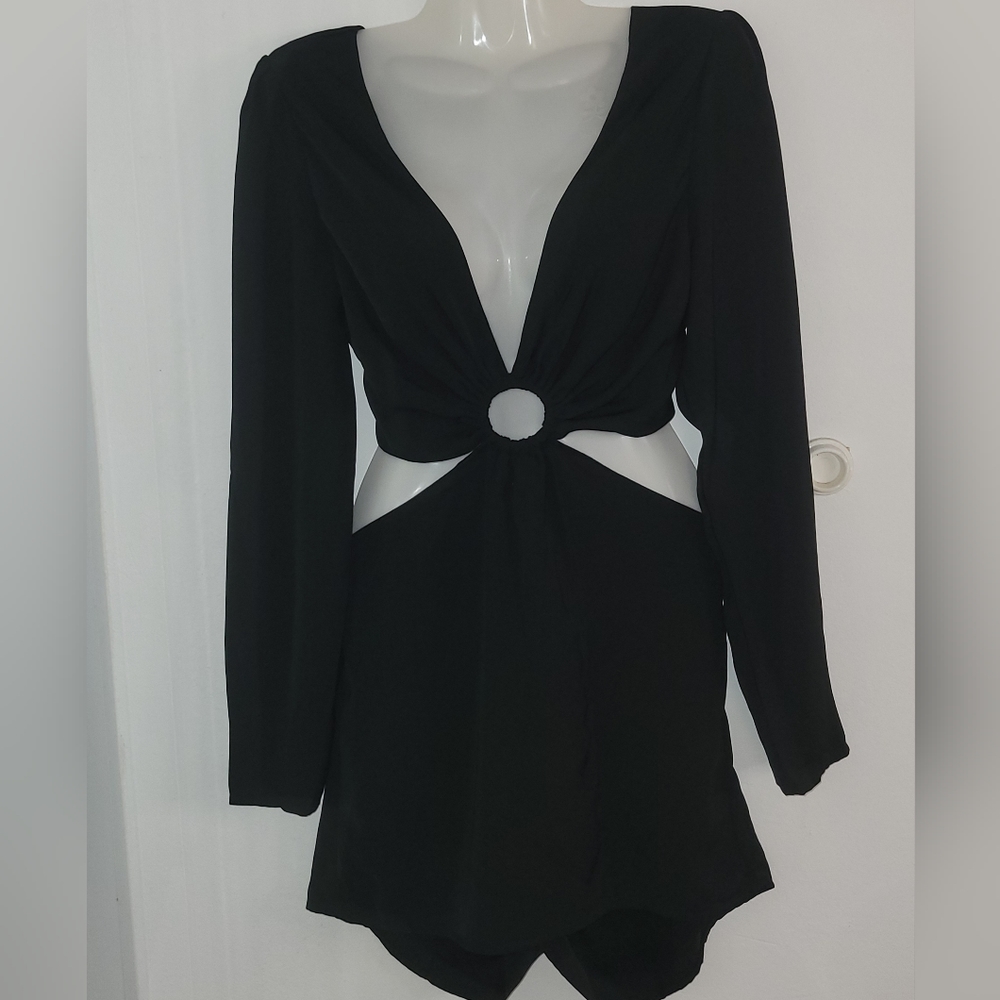 The image shows a black mini pants with long sleeves and a deep V-neckline.
